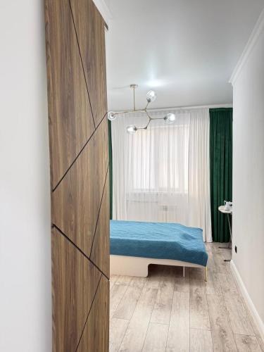 a bedroom with a blue bed in a room at Asel Residential Complex, stylish 3-room apartment in Atyraū