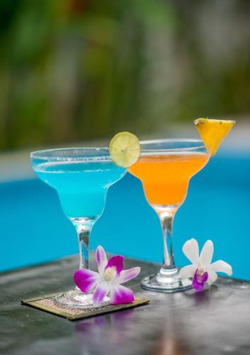 two cocktails sitting on top of a table with flowers at Reasey Boutique Villa in Siem Reap