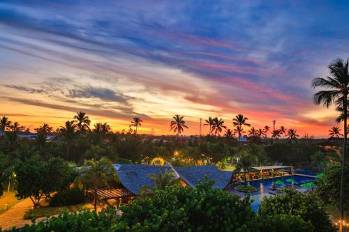 a sunset over a resort with a pool and palm trees at Vivá Porto de Galinhas Resort in Porto De Galinhas