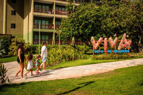 a family walking down a sidewalk in front of a building at Vivá Porto de Galinhas Resort in Porto De Galinhas
