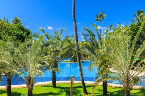 a group of palm trees next to a pool at Vivá Porto de Galinhas Resort in Porto De Galinhas