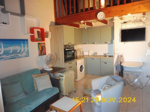 un soggiorno con un divano blu e una cucina di Les Alizes a Le Grau-dʼAgde