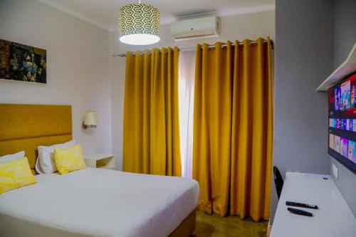 a bedroom with a bed and yellow curtains at Greenwood Manor Hotel in Ndola
