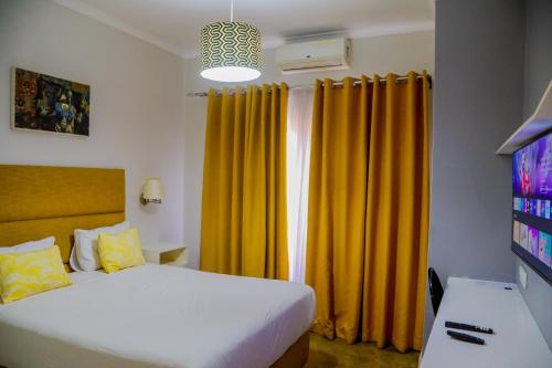a bedroom with a bed and yellow curtains at Greenwood Manor Hotel in Ndola
