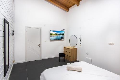 a white bedroom with a bed and a mirror at vilat hakohavim & Biktat HaKohavim in Qiryat Shemona