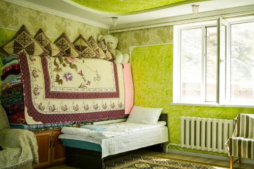 une chambre avec du papier peint vert et un lit avec une couverture dans l'établissement Salmanya, à Bokonbayevo