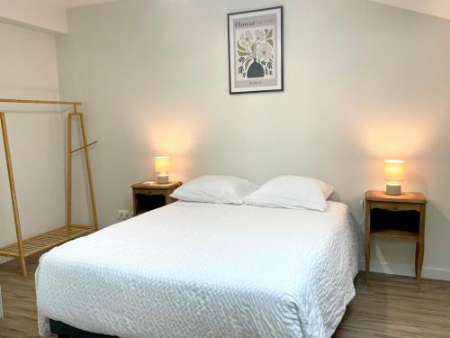 a bedroom with a white bed and two lights on two tables at Le Toué, Charme and Voie Bleue 