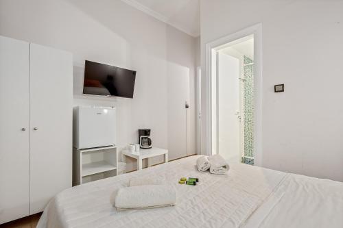 a white bedroom with a bed and a tv at SALV3R Hotel in Athens