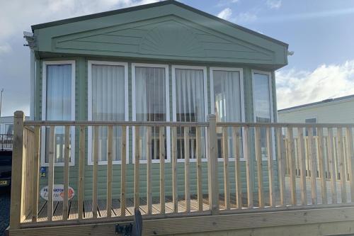 a large screened in porch with a wooden railing at Immaculate 2-Bed Lodge in Monreith in Newton Stewart