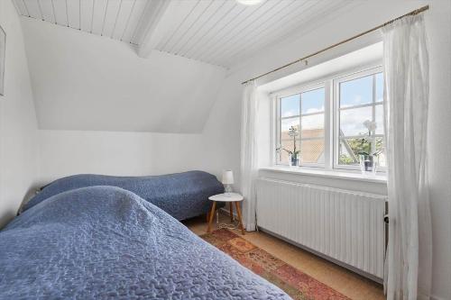 a bedroom with a blue bed and a window at 70303-Ulfborg-Jagtvejen-4 in Thorsminde