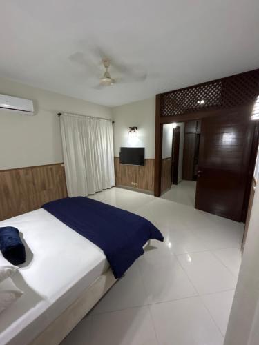 a bedroom with a large bed and a television at Tribal house in Karachi
