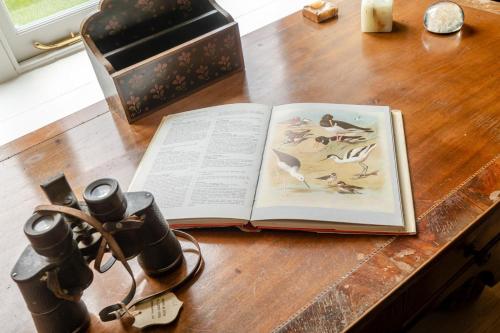 an open book on a wooden table with a camera at Park Farmhouse in Kimberley