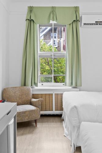 a bedroom with a bed and a chair and a window at Le Chateau de Pierre in Quebec City