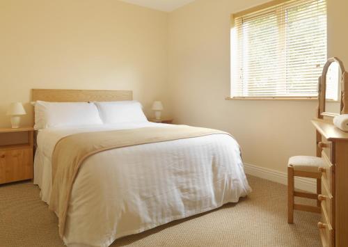 a bedroom with a bed with white sheets and a window at Tralee Town Centre Apartments in Tralee