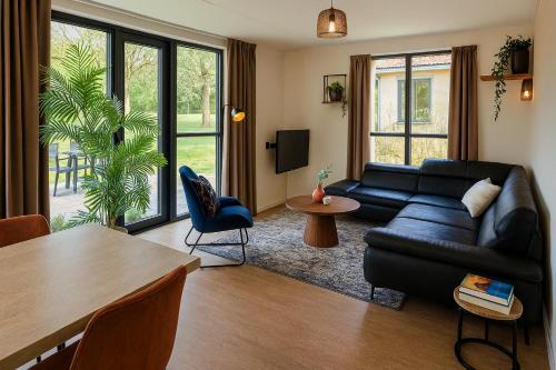 a living room with a black couch and a table at Lakefront Cottage Gelderland BBQ & tuin 6pers in Ewijk