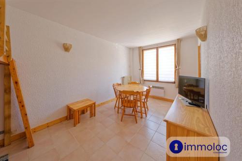 Una sala de estar con una mesa y un televisor. en Charming studio in Auron, en Auron
