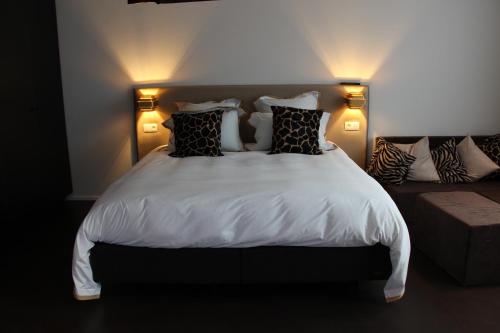 a bedroom with a white bed with pillows and a couch at Koto Garden Suites in Antwerp