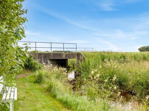 a bridge over a field with a bench in the grass at Holiday Home Saran - 30km from the sea by Interhome in Toftlund