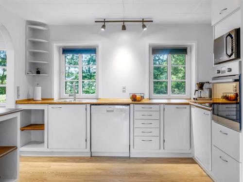 a white kitchen with white cabinets and windows at Holiday Home Saran - 30km from the sea by Interhome in Toftlund