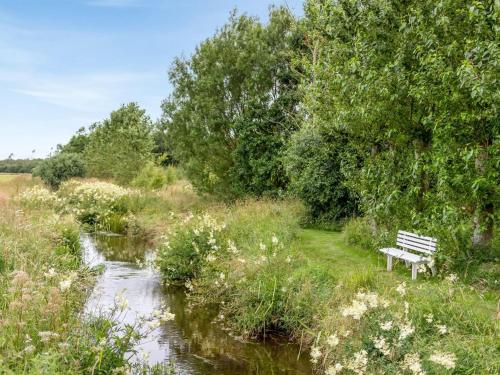 a park bench sitting next to a river at Holiday Home Saran - 30km from the sea by Interhome in Toftlund