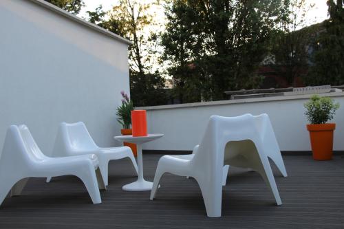 three white chairs and a table on a patio at Koto Garden Suites in Antwerp