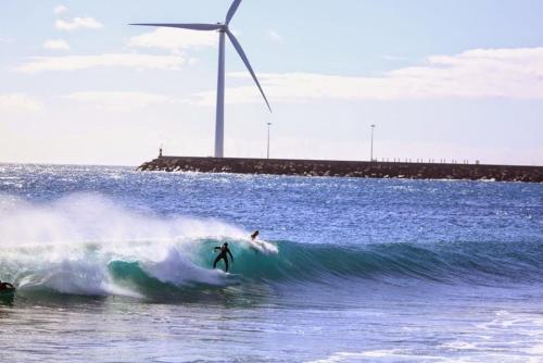 a person riding a wave on a surfboard in the ocean at Hotel Playa de Arinaga in Arinaga