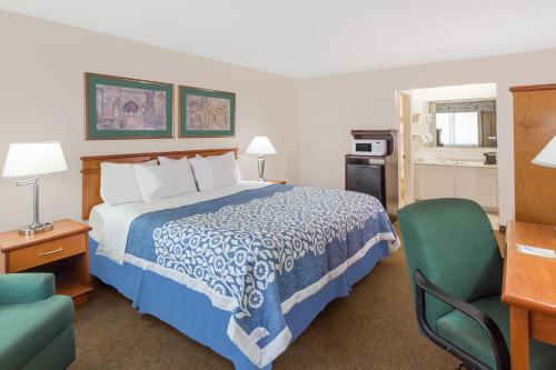 a hotel room with a bed and a green chair at Days Inn by Wyndham Fort Myers Springs Resort in Estero