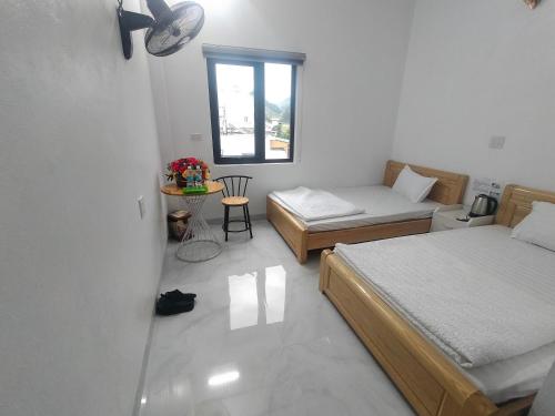 a small bedroom with two beds and a window at Hoa Sơn Tra Hotel in Mù Cang Chải
