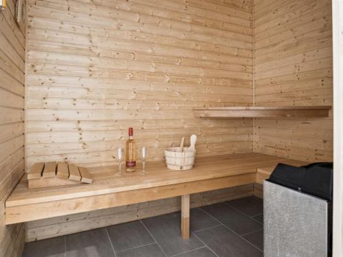 a wooden bench in a sauna with a bottle of wine at Holiday Home Alka - 500m from the sea by Interhome in Sjølund
