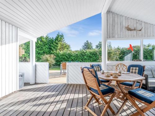 a white porch with a wooden table and chairs at Holiday Home Ion - 250m from the sea by Interhome in Vordingborg
