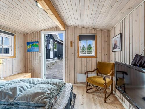 a bedroom with a bed and a chair at Holiday Home Tenho - 150m from the sea by Interhome in Strøby