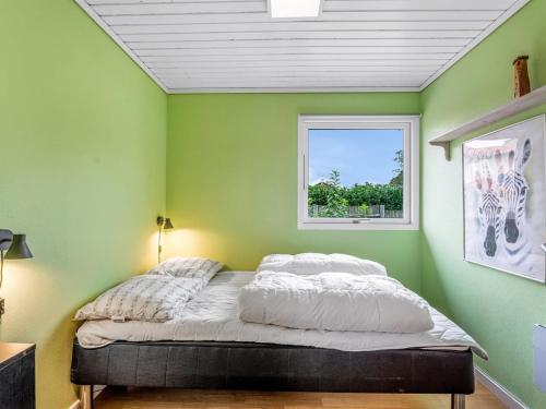 a bedroom with green walls and a bed with a window at Holiday Home Tenho - 150m from the sea by Interhome in Strøby