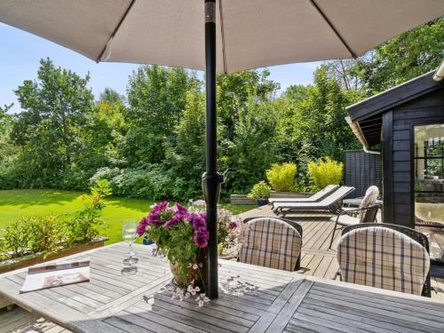 a wooden table with an umbrella on a patio at Holiday Home Bedine - 1-3km from the sea by Interhome in Gilleleje