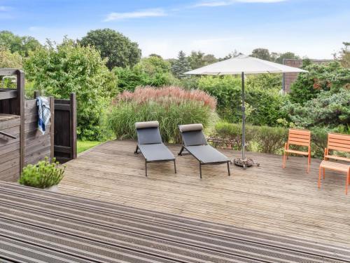 two chairs and an umbrella on a wooden deck at Holiday Home Yardila - 1-4km from the sea by Interhome in Tisvildeleje