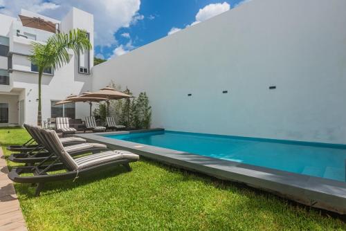 una piscina con sedie a sdraio accanto a una casa di Malibu Residential 3BD - Lia a Cozumel