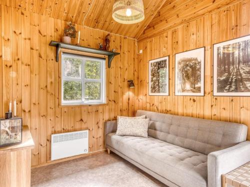 a living room with a couch in a wooden wall at Holiday Home Unge - 2-9km from the sea by Interhome in Blokhus