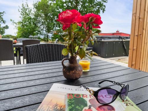 a vase with a flower on a table with a book and glasses at Holiday Home Wilgrib - 50m from the sea by Interhome in Rønne