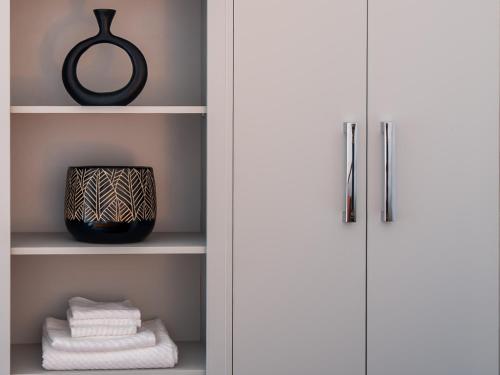 a closet with white towels and a black mirror at Luxury ground floor modern flat close to city with free parking in Leeds