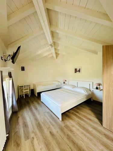 a bedroom with a large white bed and wooden floors at Giardini B&B in Modena