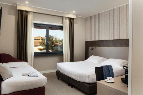 a hotel room with two beds and a window at Eurogarden Hotel in Rome