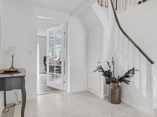 a white hallway with a vase with a plant in it at Holiday Home Vinni - 25km from the sea by Interhome in Rødding