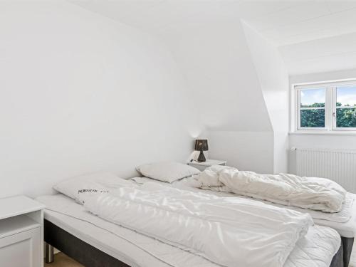 a large bed with white sheets and a window at Holiday Home Vinni - 25km from the sea by Interhome in Rødding
