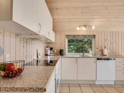 a kitchen with white cabinets and a bowl of fruit on the counter at Holiday Home Skrollan - 200m to the fjord by Interhome in Sindrup