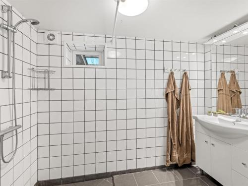 a white tiled bathroom with a shower and a sink at Holiday Home Slavomira - 12km from the sea by Interhome in Bredebro