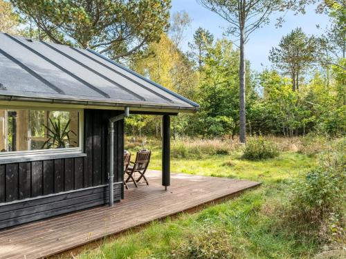 a cabin with a deck and a chair on it at Holiday Home Reinfried - 250m from the sea by Interhome in Jerup