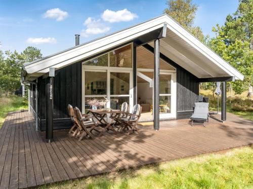 a cabin with a deck with chairs and a table at Holiday Home Reinfried - 250m from the sea by Interhome in Jerup
