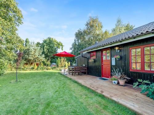 a house with a deck and a red umbrella at Holiday Home Heraldine - 400m from the sea by Interhome in Stubbekøbing