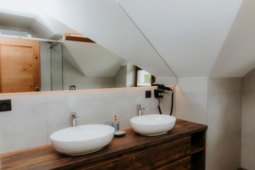 a bathroom with two white sinks on a wooden counter at Chata Stromček in Zuberec