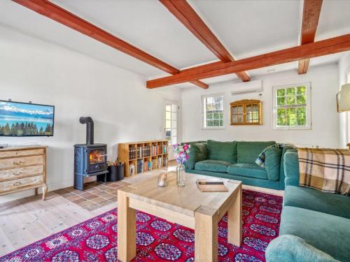a living room with a green couch and a wood stove at Holiday Home Waldemar - 8km from the sea by Interhome in Gudhjem