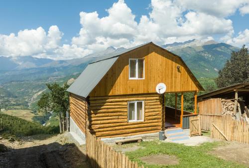 a small wooden house with mountains in the background at Cottage "Labskaldi-Laila" 